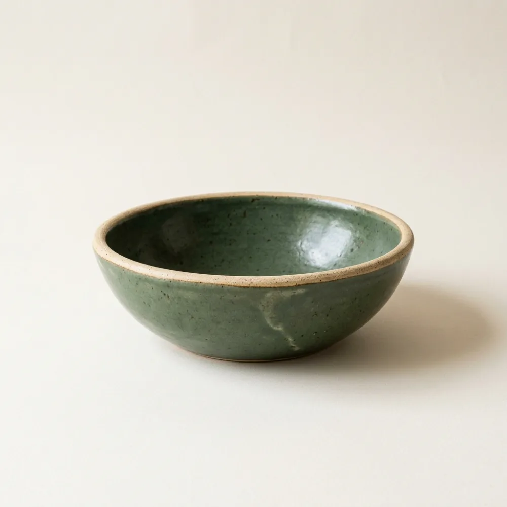 Wide sage green ceramic serving bowl with a sandy rim